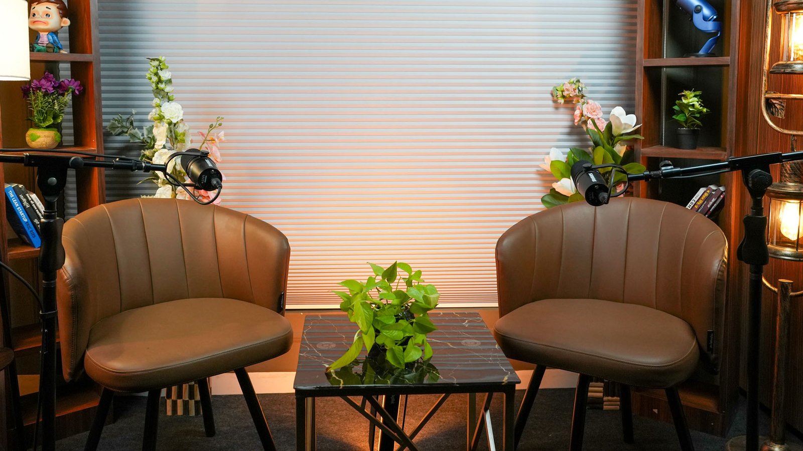 Podcast set with two tan armchairs, a coffee table with a plant and a microphone