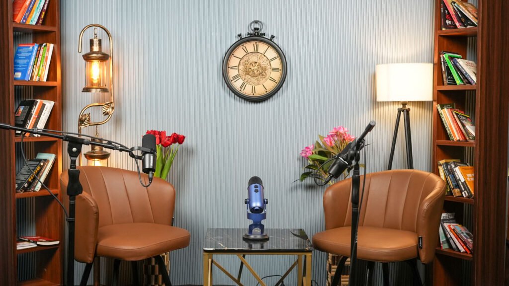 Armchairs and a coffee table with a small statue and flowers in the light podcast set