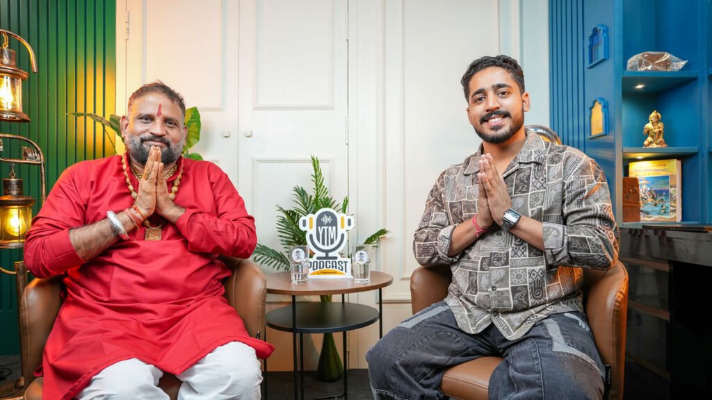 Two men greeting with folded hands in a bright set with white panels and plants